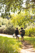 © Wavebreak Media - Two people are hiking on a sunny trail surrounded by lush greenery, collecting trash, with copy spac