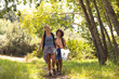 © Wavebreak Media - Two women are walking on a forest trail, one with blonde hair, the other with curly dark hair, colle