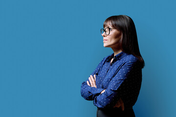 Profile view of middle aged serious woman, blue background, copy space