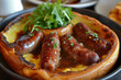 A plate of toad in the hole, a traditional English dish made of sausages baked in a Yorkshire pudding batter