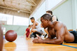 © Marko Geber - Exhausted basketball player resting on the court with teammates