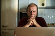 © Marko Geber - Concentrated middle-aged man working on laptop in home kitchen