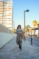 Woman Walking Down Sidewalk Next to Tall Building with a Easel