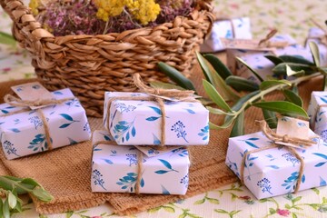 Wall Mural - Wedding favors guest gifts wrapped herbal style olive leaves pattern paper jute ribbon, guest gifts boxes artisan soaps, beautiful packaging, white blue green colors, rustic mediterranean style party