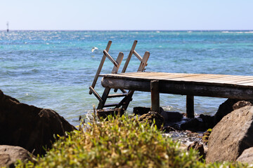 Wall Mural - Dock with stairs leading into the blue Aruban ocean.