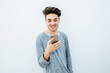 Portrait of young boy using mobile phone in front of white wall.