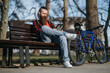 © qunica.com - Remote working concept with a male entrepreneur using a tablet outdoors next to his bike in a city park.