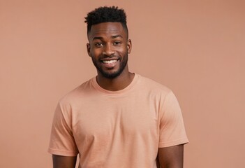 Canvas Print - Casual young man with an open, engaging smile, peach backdrop. His relaxed demeanor and smile are inviting.