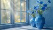 Two blue vases with blue flowers near blue shabby wall and a window