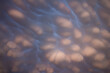Mammatus clouds in the sky overhead create an other worldly display. Light from the setting sun gives them a pink hue.