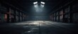 A large, empty industrial warehouse is shrouded in darkness, with a single light shining at the far end, illuminating the space and creating a stark contrast between light and dark.