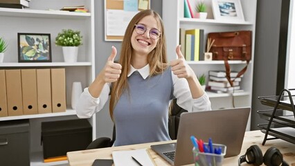 Wall Mural - Cheerful young blonde business woman making heart shape with hands - a romantic concept in the office