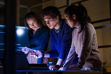 group of modern young it specialists developing and testing new software late in evening
