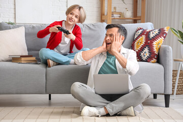 Sticker - Working young man stressed of his noisy little son playing video game at home