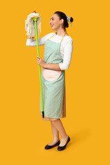 Sticker - Portrait of happy young housewife in apron with mop on yellow background