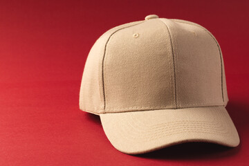 Wall Mural - A beige baseball cap is positioned against a red background, with copy space