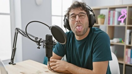 Poster - Beaming young hispanic guy tunes in to his pensive thoughts while rocking headphones in a buzzing radio studio, looking away with a confident smirk.