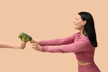 Sticker - Beautiful young happy woman and hand with fresh broccoli on beige background. Weight loss concept