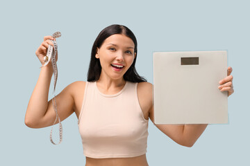 Poster - Beautiful young happy woman with measuring tape and scales on blue background. Weight loss concept