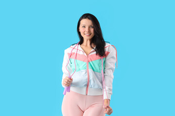 Poster - Sporty young woman with skipping rope on blue background