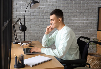 Sticker - Happy young man in wheelchair working with laptop at home