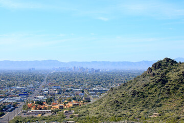 Wall Mural - High rise buildings of Phoenix downtown in the Valley of the Sun with a backdrop of South Mountains as seen from North Mountain Park hiking trails on a sunny Spring morning, Arizona