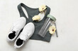 Composition with sports bra, shoes, bottle of water and flowers on light background. International Women's Day