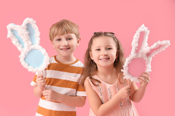 Wall Mural - Cute little children with paper bunny figures on pink background. Easter celebration