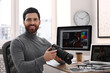 © New Africa - Professional photographer with digital camera at table in office
