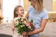 © New Africa - Little daughter congratulating her mom with bouquet of alstroemeria flowers in kitchen. Happy Mother's Day
