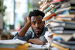 © lucky pics - Young adult African American man in an office, overwhelmed by a mountains of paperwork