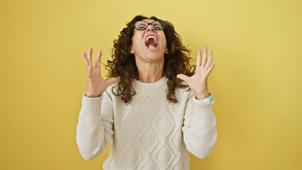 Sticker - Furious middle age hispanic woman in glasses, going berserk, standing, yelling in deep frustration, arms raised madly. isolated yellow backdrop screaming deed.