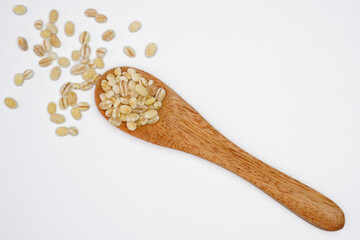 Pearl barley grain seeds in a wooden spoon concept background