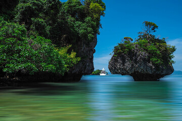 Wall Mural - Aerial panorama of Thailand's verdant, lush tropical island, National Park Island, with blue and aquamarine the sea, and clouds shining by sunlight in the background.