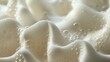 Close-up of a white, creamy substance with a smooth, velvety texture. The surface is dotted with tiny bubbles.