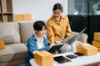© Nuttapong punna - Startup small business SME, Entrepreneur owner two woman using smartphone or tablet taking receive and checking online purchase shopping order