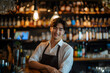 Young Korean male bartender standing in front of the bar smiling at work  