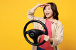© ViDi Studio - Young woman of Asian ethnicity wear pink t-shirt beige shirt pastel casual clothes hold steering wheel driving car look far away isolated on plain yellow background studio portrait Lifestyle portrait
