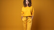 Confident woman in a monochromatic yellow sporty outfit with a relaxed pose and a beaming smile.