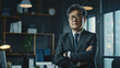 © VK Studio - Confident Asian businessman in a modern office, arms crossed and looking thoughtfully at the camera.