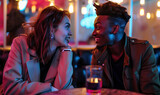 Fototapeta Uliczki - Close-up, young stylish trendy couple in a modern European bar on a date after work. Woman and man are relaxed, smiling, sitting across from each other, date night, isolated shot, bokeh, neon lighting