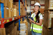 © offsuperphoto - portrait worker working on tablet and looking at cardboard box on shelf in warehouse storage
