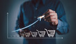 © Nirusmee - Businessman drawing increasing trend graph of sale volume with bigger shopping trolley cart for online sale business growth concept..