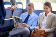 Business people, man and woman in bus or public transport for travel and commute outdoors against blurred background. Colleagues, working partners with newspaper and phone for thinking on trip