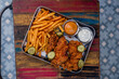 portrait photography of a tray filled with fried chicken and fries with mayo and mustard, shot in high angle