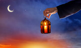 Fototapeta Na ścianę - Hand holding  Arabic Ramadan Lantern. Decoration lamp. Crescent moon and the stars. Islamic greeting Eid Mubarak cards for Muslim Holidays.Eid-Ul-Adha festival celebration