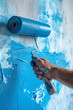Hand hält Malerrolle mit blauer Farbe