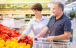Mature family of retirees examines bell pepper in grocery section of a supermarket
