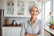 © Darya - Positive senior woman smiling in the kitchen