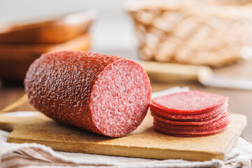 Poster - Sliced smoked salami sausages on cutting board on wooden table.